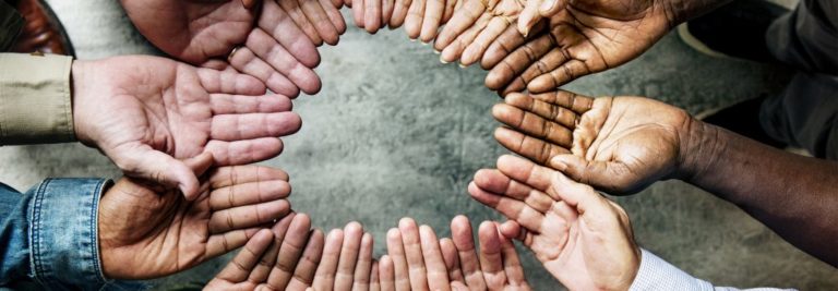 group of people making a circle with their open palms by standing together in a circle