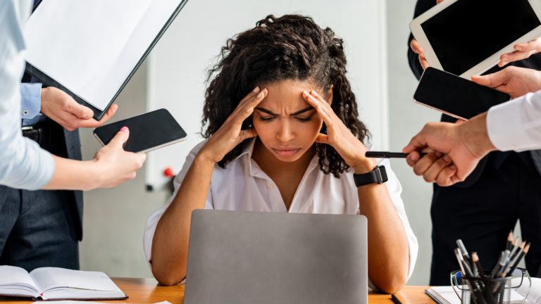 Businesswoman being overworked | Causes of Employee Burnout | Limeade