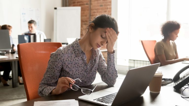 Frustrated woman working on laptop | Employee Burnout Statistics for 2022 | Limeade