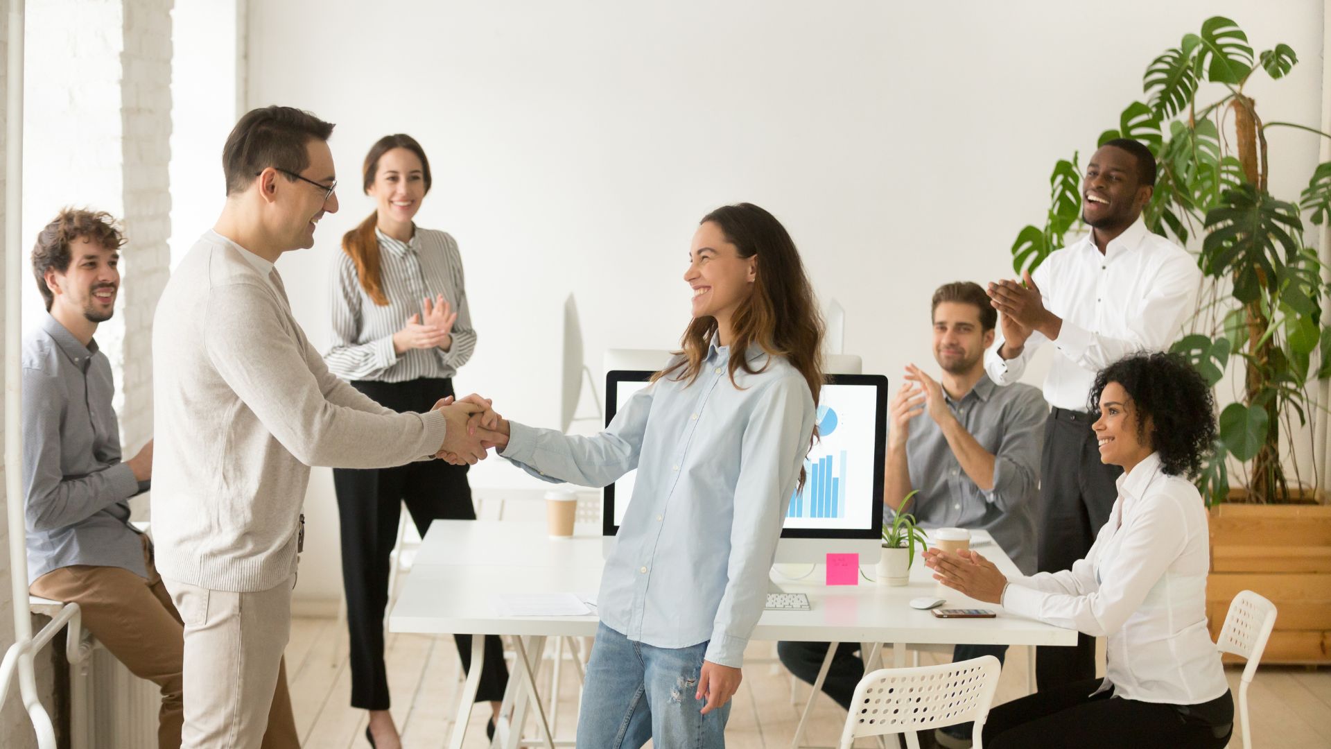 Group of employees cheering for their coworker as she shakes boss’ hand | Holistic Employee Wellness | Limeade
