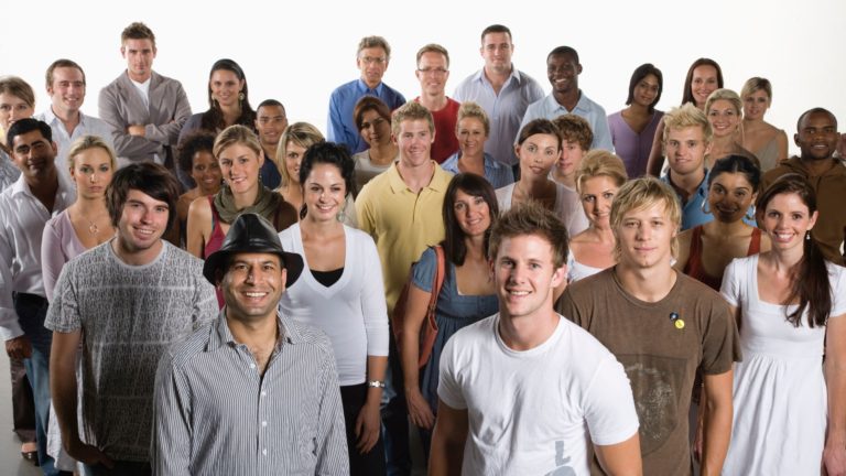 Diverse group of people huddled together smiling at camera | Holistic Employee Wellness | Limeade