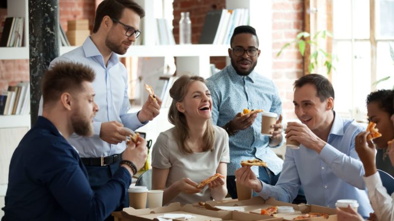 Group of employees laugh while eating pizza together | Holistic Employee Wellness | Limeade