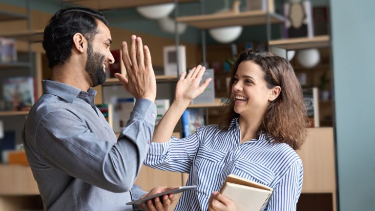 Two employees high-five in the office | Holistic Employee Wellness | Limeade