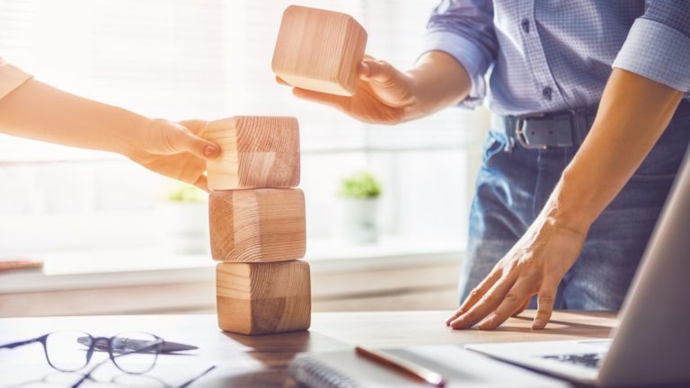Employees stacking building blocks in the workplace | Limeade well-being programs