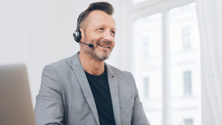 Manager wearing headset smiles while chatting with Limeade support team | Organizational Culture