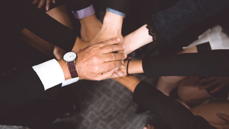 Aerial view of team of engaged employees piling their hands together | Organizational Culture