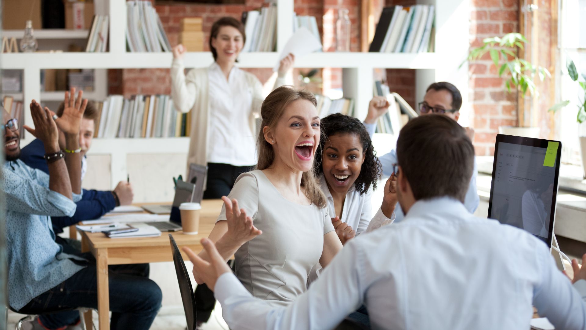 Team of happy employees cheering together during meeting | Organizational Culture